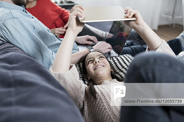 Mädchen mit Familie auf Sofa liegend mit Tablette