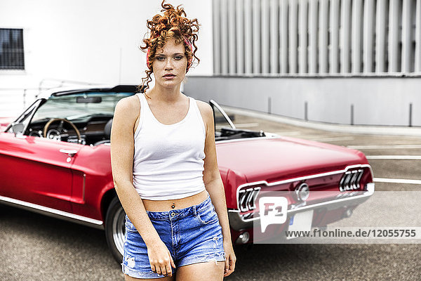 Portrait of redheaded woman at sports car