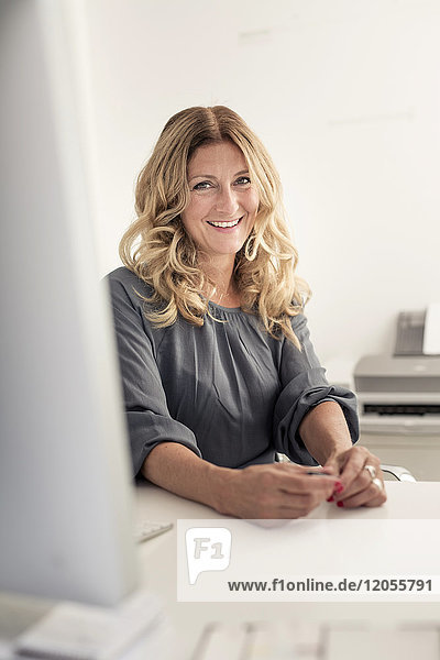 Porträt einer lächelnden Geschäftsfrau am Schreibtisch im Büro