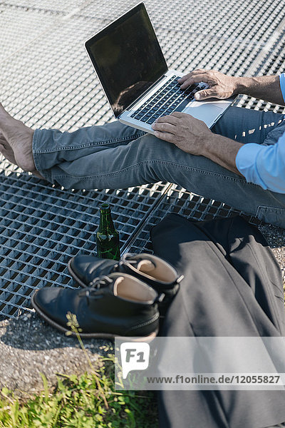 Mann mit Bier und Laptop im Freien