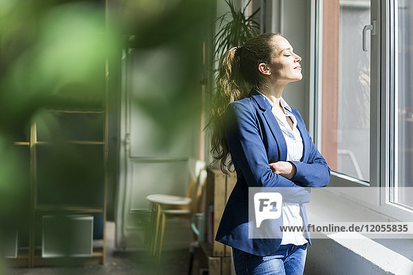 Businesswoman standing with closed eyes at the window