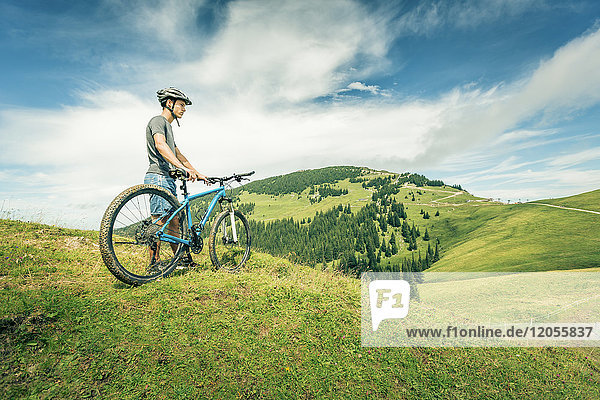 Germany  Bavaria  Pfronten  young man with mountain bike on alpine meadow near Aggenstein