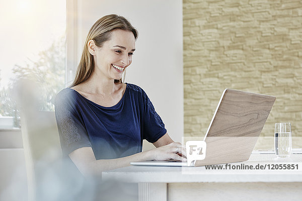 Happy woman at home using laptop