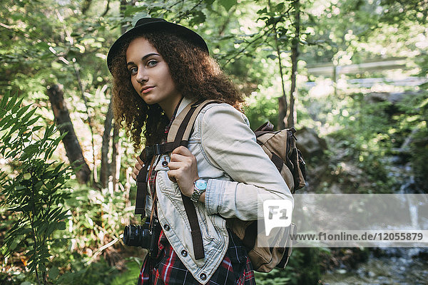 Portrait of teenage girl with backpack and camera in nature