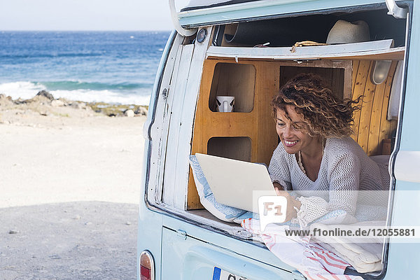 Spanien  Teneriffa  glückliche Frau mit Laptop im Van