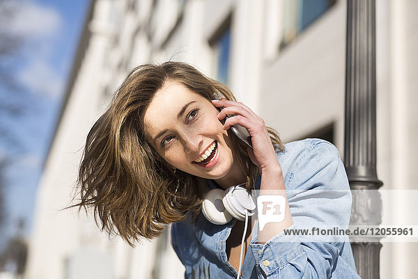 Porträt der lachenden Frau mit Kopfhörer am Telefon