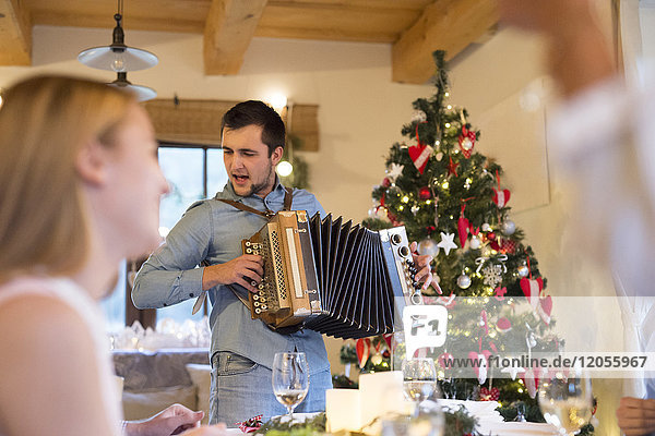Young man playing accordion at Christmas dinner table