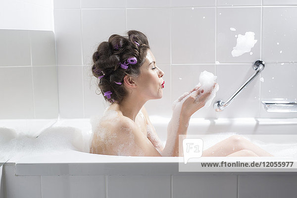 Young woman with curlers taking a bath