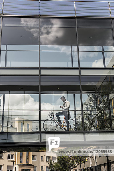 Geschäftsmann mit Handy und Fahrrad im Bürogang