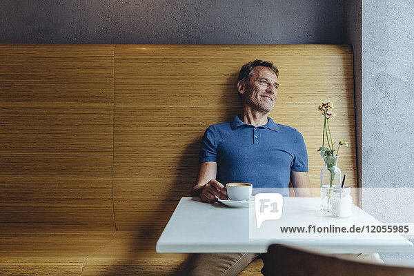 Entspannter reifer Mann sitzt im Café