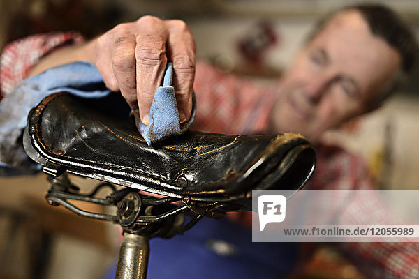 Senior Mann beim Reinigen des Fahrradsitzes in seiner Werkstatt  Nahaufnahme