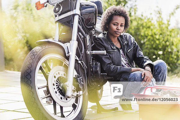 Porträt einer jungen Frau mit ihrem Motorrad