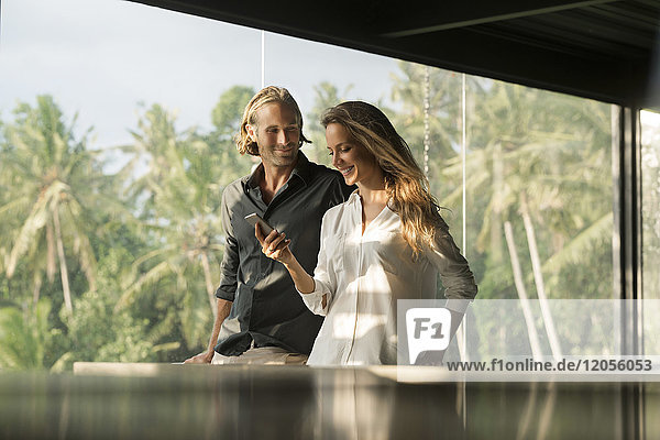 Lächelndes Paar mit Smartphone im Designhaus