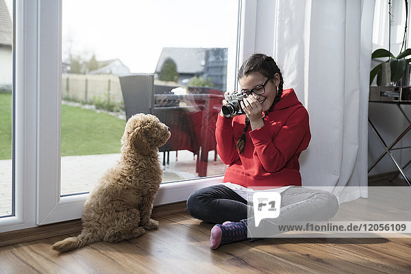 Mädchen beim Fotografieren ihres Hundes im Wohnzimmer