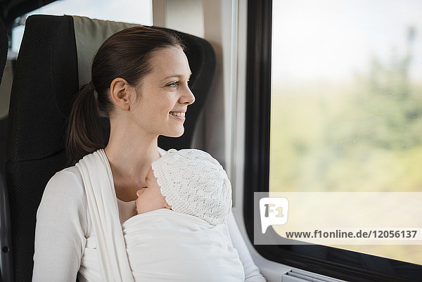 Mother with baby girl traveling by train looking out of window