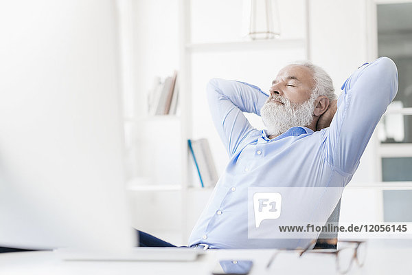 Erwachsener Mann mit Bart entspannt am Schreibtisch