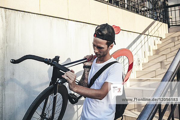 Young man carrying fixie bike downstairs