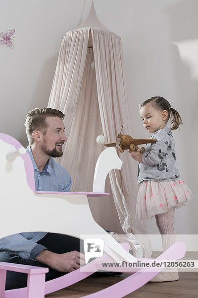 Vater spielt mit Kleinkind-Tochter in ihrem Kinderzimmer