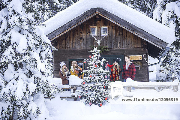 Austria  Altenmarkt-Zauchensee  friends decorating Christmas tree at wooden house