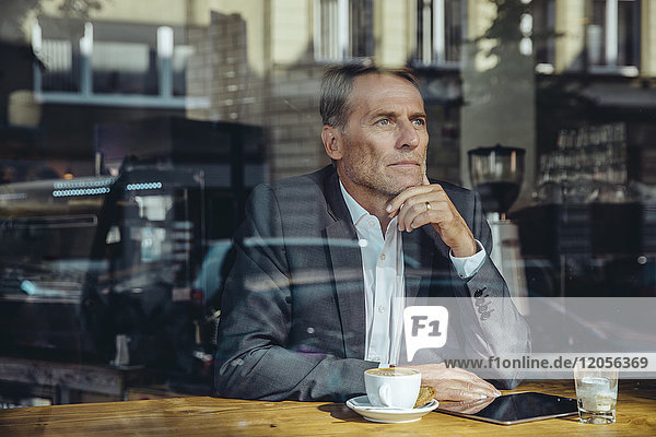 Seriöser Geschäftsmann im Cafe mit Blick aus dem Fenster