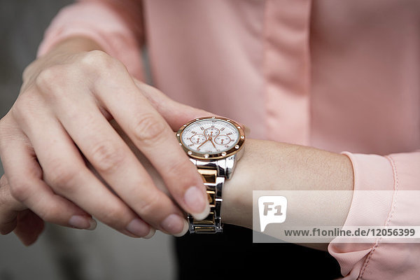Porträt einer jungen Geschäftsfrau mit Blick auf ihre Armbanduhr