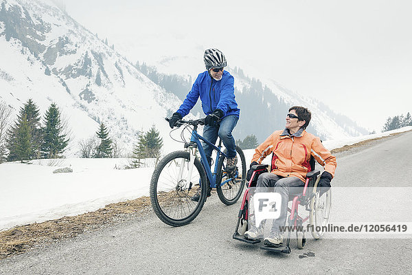 Austria  Damuels  senior couple with bike and wheelchair enjoying a winter day