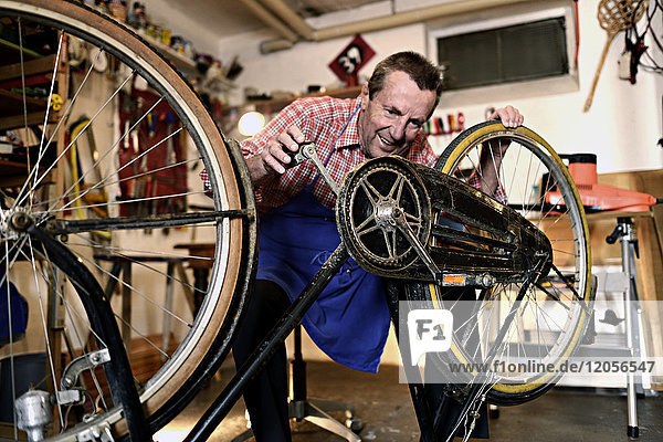 Älterer Mann beim Radfahren in seiner Werkstatt