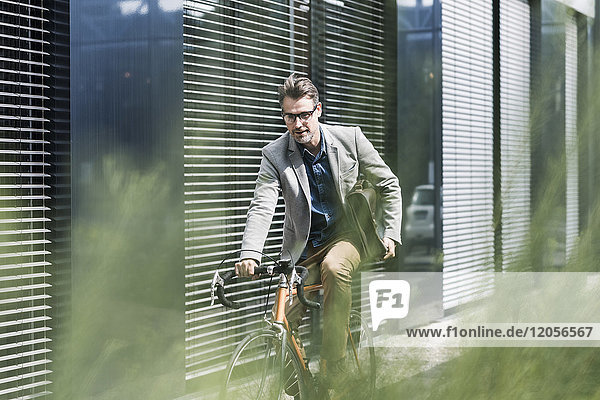 Schockierter Geschäftsmann auf dem Fahrrad beim Blick aufs Handy