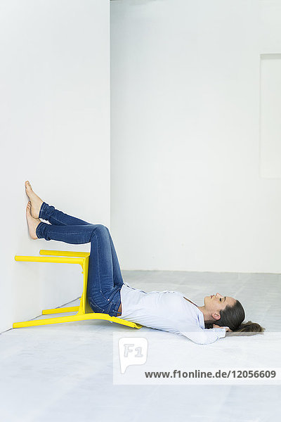 Frau auf dem Boden liegend mit einem gelben Stuhl