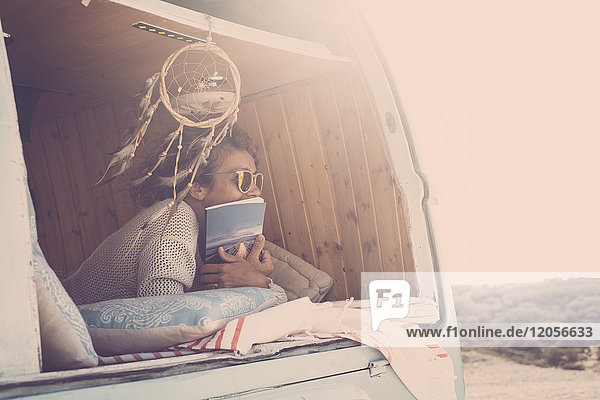 Spanien  Teneriffa  Frau mit Buch im geparkten Van bei Dämmerung