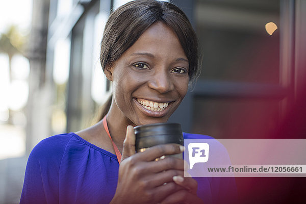 Porträt einer lächelnden Geschäftsfrau mit Kaffeetasse