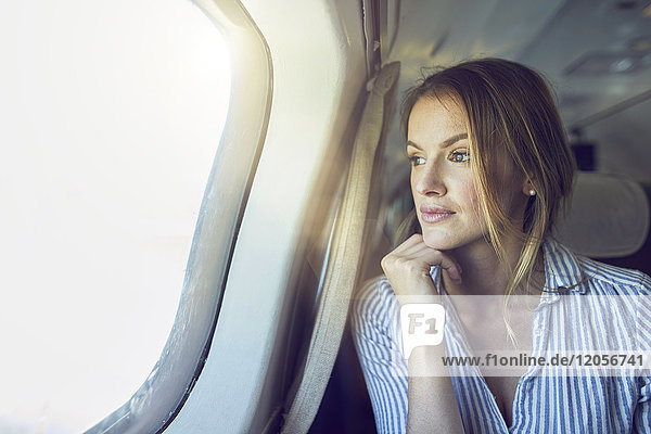 Ernsthafte Frau schaut aus dem Flugzeugfenster