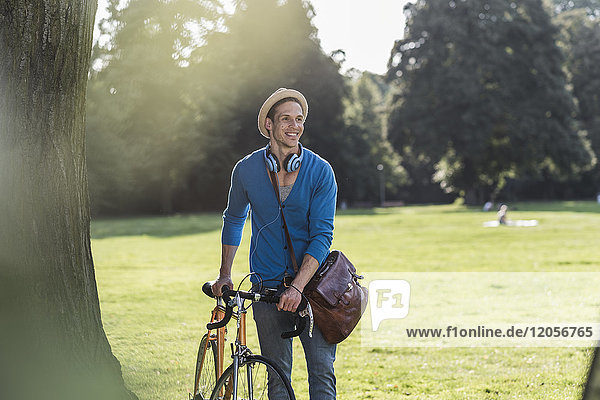 Portrait of relaxed man with racing cycle in a park