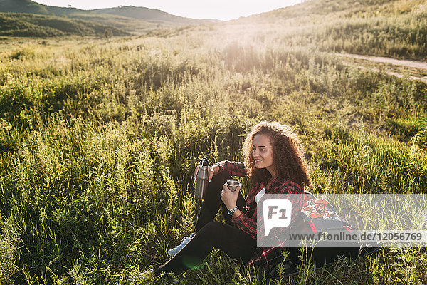 Teenage girl with thermos flask having a rest in nature