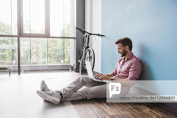 Man using laptop sitting on the floor in office