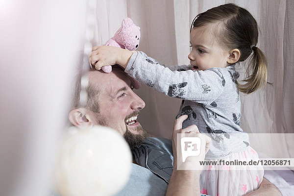 Glücklicher Vater spielt mit Kleinkind-Tochter im Spielzeug-Teepee