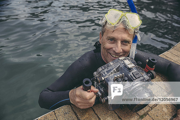 Porträt eines glücklichen Mannes mit Unterwasser-DSLR-Kameragehäuse im Wasser