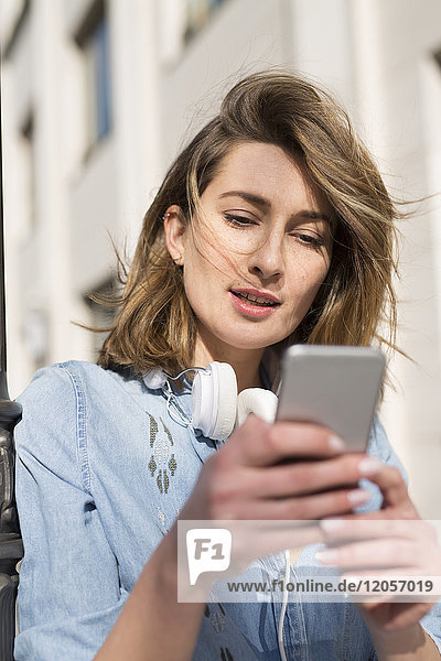 Portrait of woman with headphones looking at cell phone