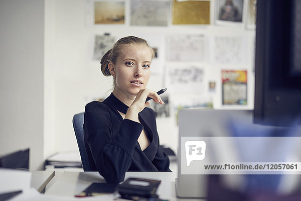 Porträt einer jungen Geschäftsfrau am Schreibtisch im Büro