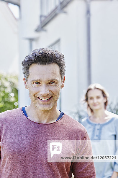 Portrait of smiling man with woman in background