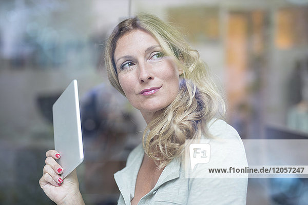 Geschäftsfrau hält Tablette hinter Fensterscheibe