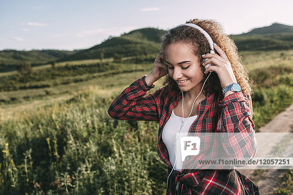 Teenagermädchen beim Musikhören mit Kopfhörern in der Natur