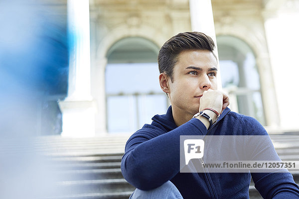Portrait of pensive young man sitting on stairs