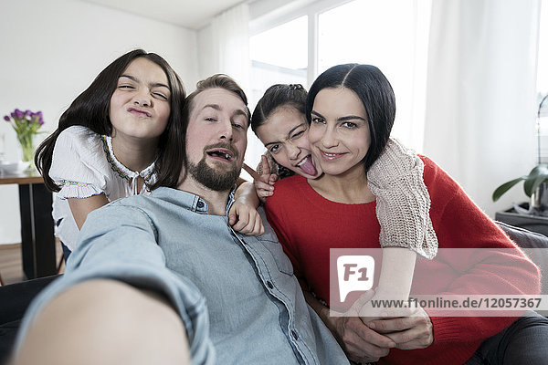 Eltern und Zwillingstöchter  die mit einem Selfie herumspielen.