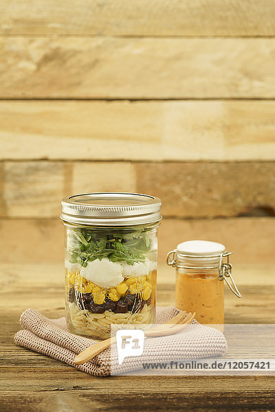Glas vegetarischer gemischter Salat mit Kritharaki  Mais  Rucola und Preiselbeeren und Glas Cocktailsauce