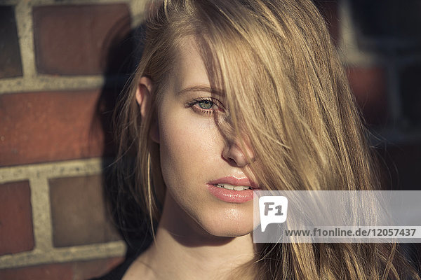 Porträt einer blonden jungen Frau vor der Backsteinmauer
