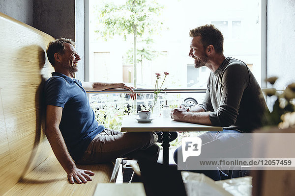 Zwei Männer sitzen im Café und reden miteinander.