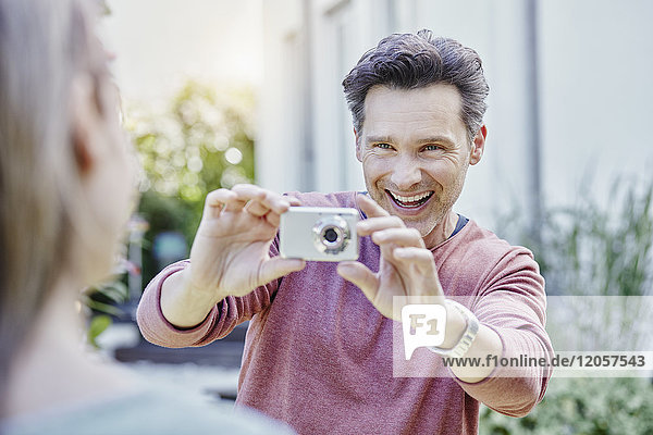 Glücklicher Mann  der seine Frau im Freien fotografiert.