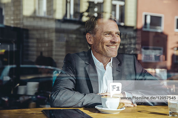 Smiling businessman in cafe looking out of window