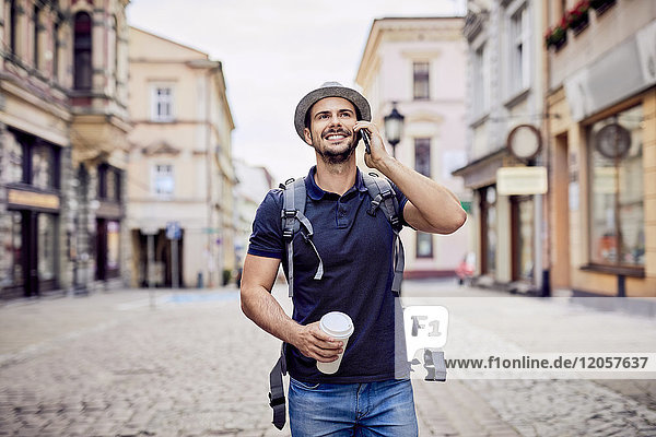 Traveler talking on the phone while walking down city street